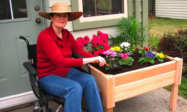 woman in wheelchair planting flowers in her garden