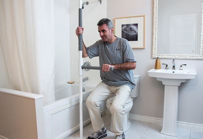 man using safety pole in bathroom to get off of toilet