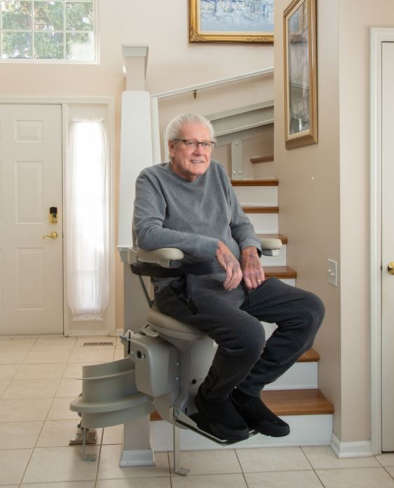 man riding stairlift in his home